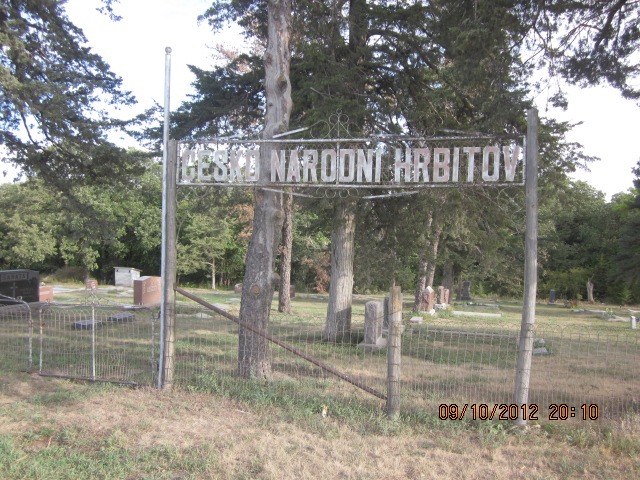 cemetary sign in Bohemian, with gravestones and pine trees