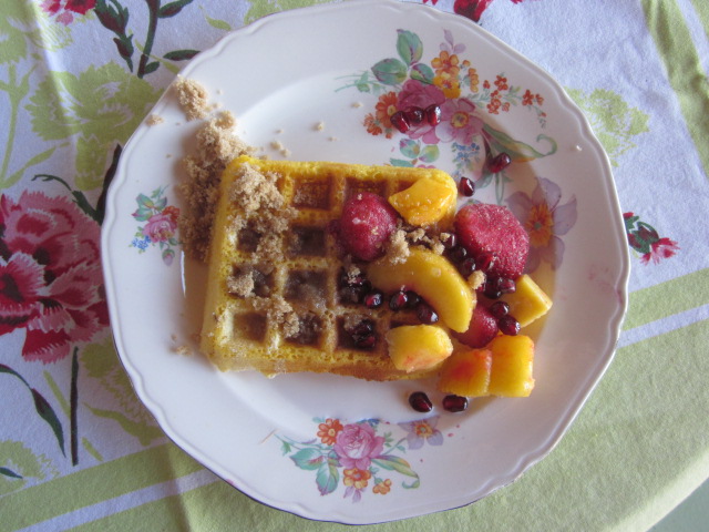 waffle on a plate with fruit, cream, and brown sugar