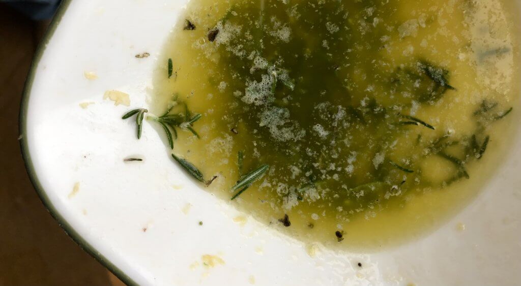 bowl of melted butter with rosemary and garlic