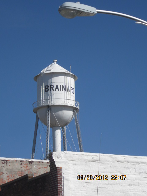 white water tower with Brainard painted on the side, blue sky