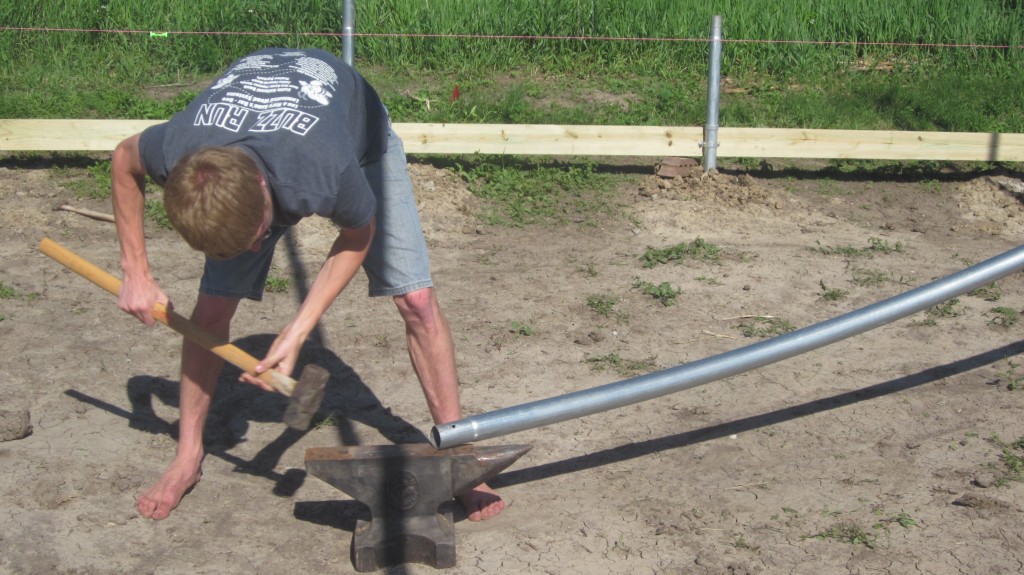 Timothy tries his hand at shaping the end of the pipe on the anvil.