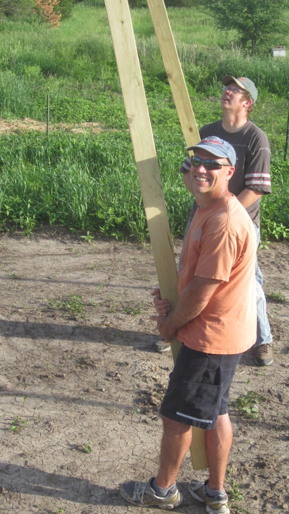 Bryan and Dave grab boards to prop up the purlin so Timothy can install it.