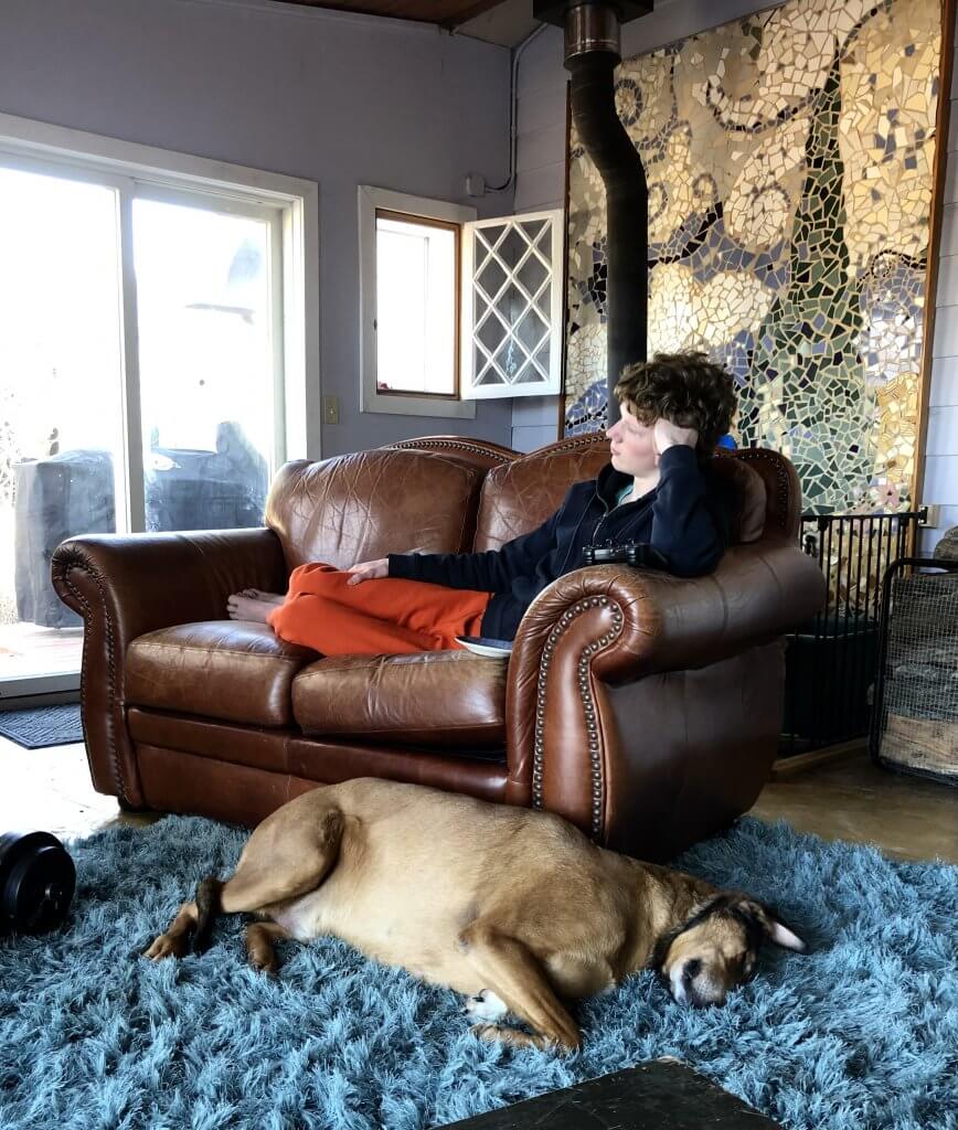 dog lying next to couch, teen boy on the couch