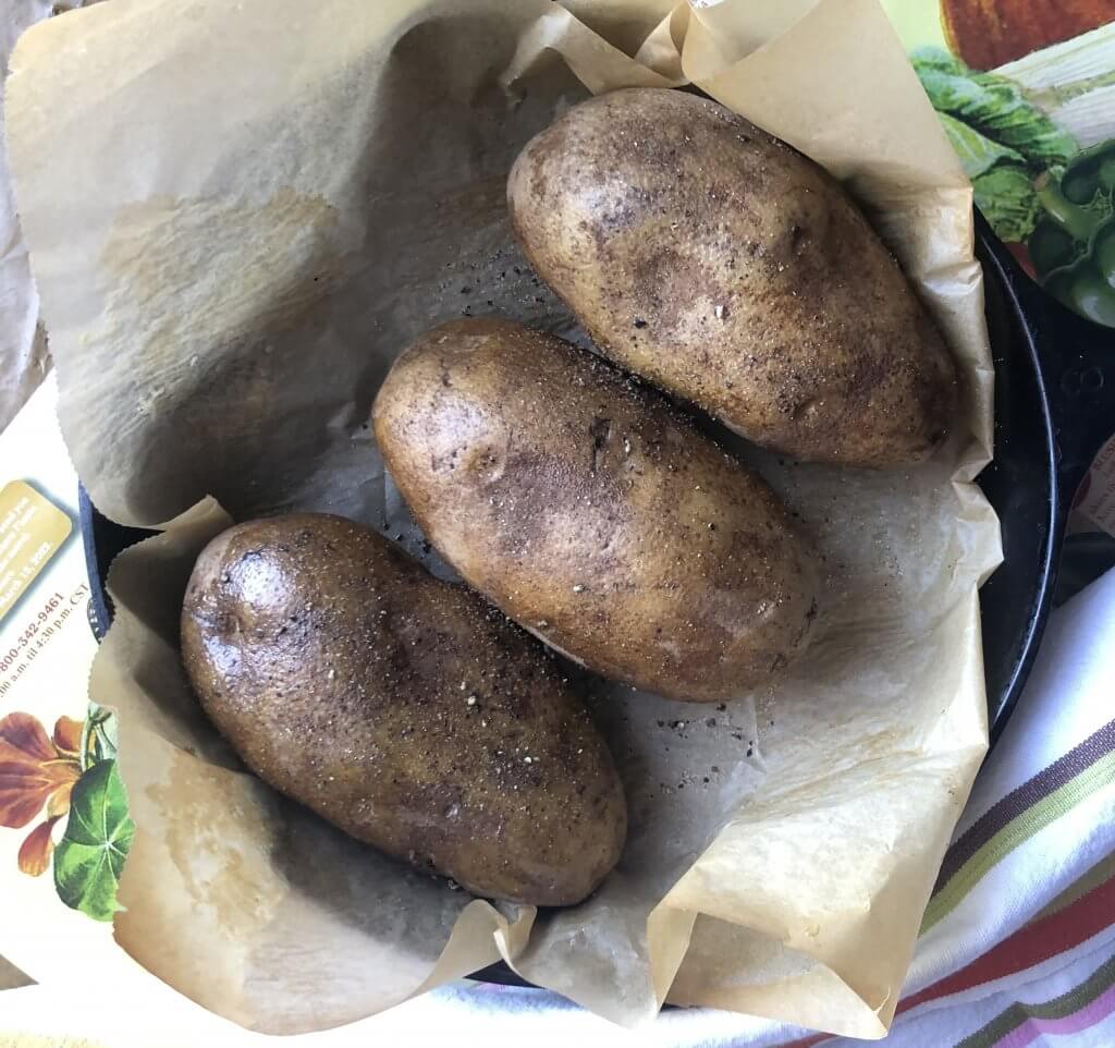 three potatoes in pan ready to be baked