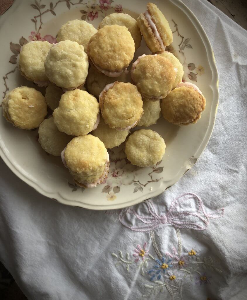 plate with little sandwich cookies, pink filling, on an embroidered cloth