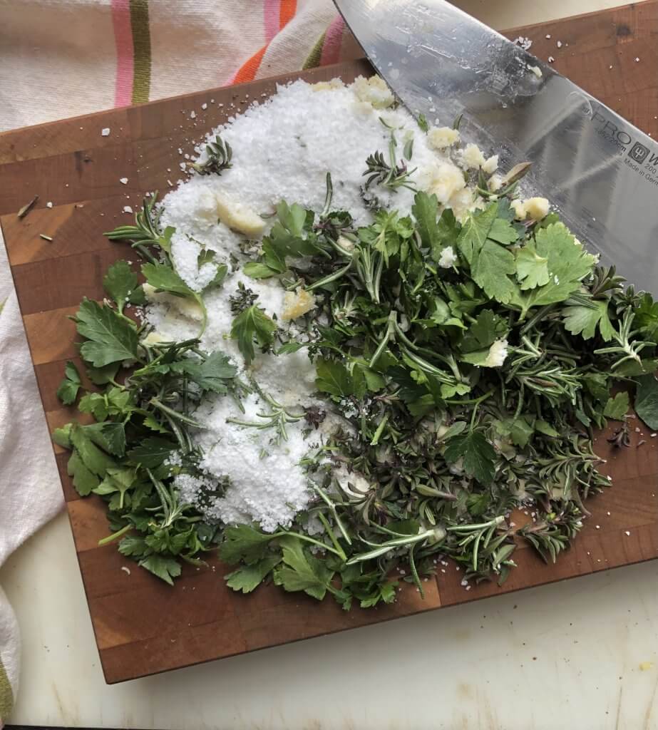 board with salt and fresh herbs and chef's knife