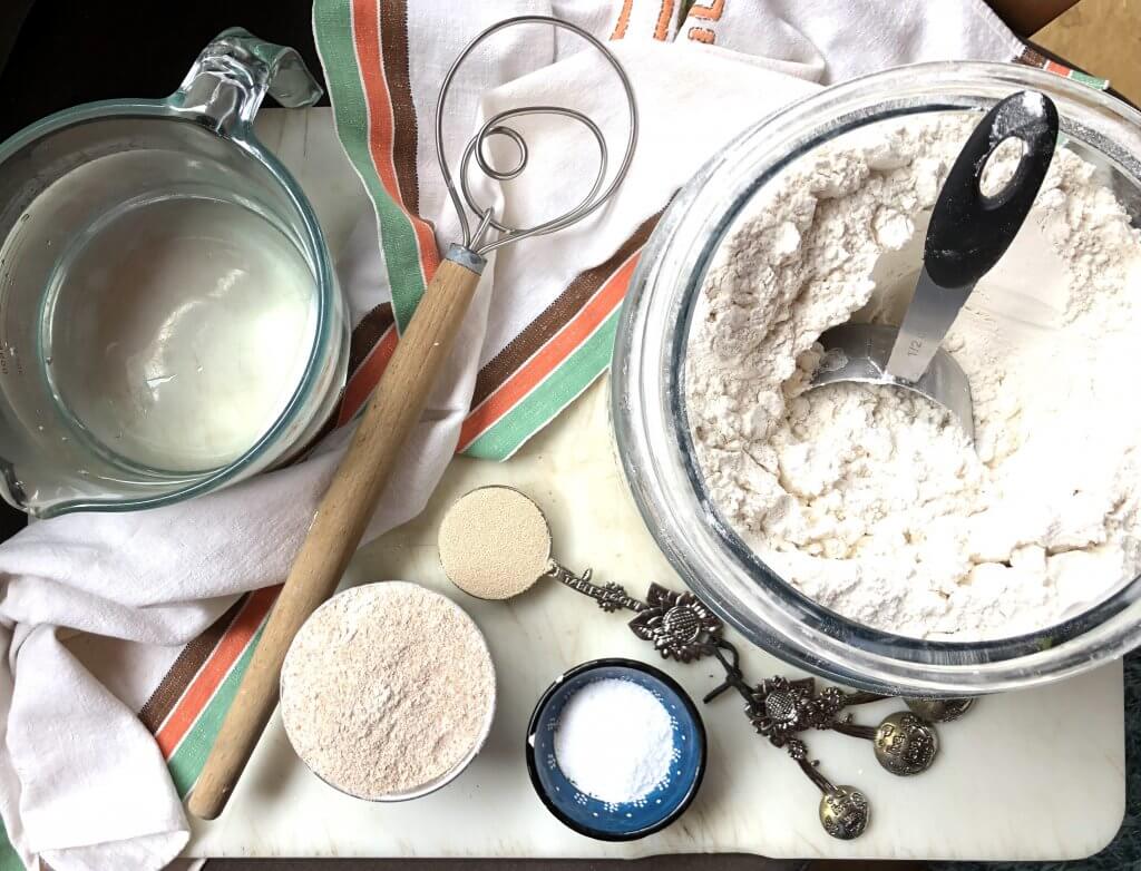 still life of flour, yeast, and mixing supplies on white board