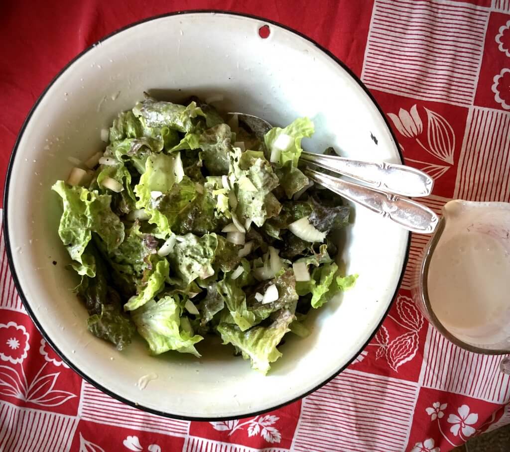 white bowl full of green salad, on a red tablecloth