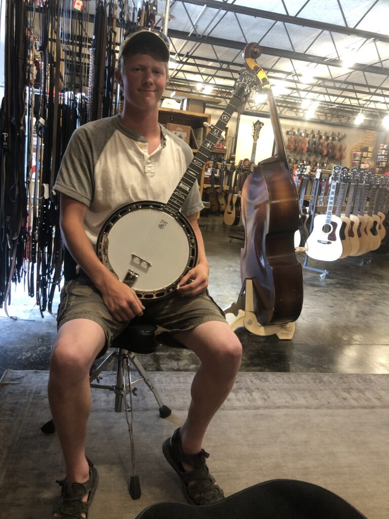 young man holding banjo in guitar store