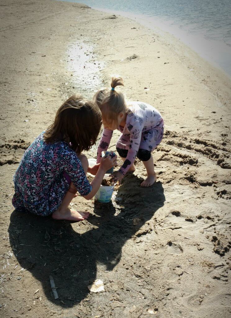 two little girls playing on a sandy beach