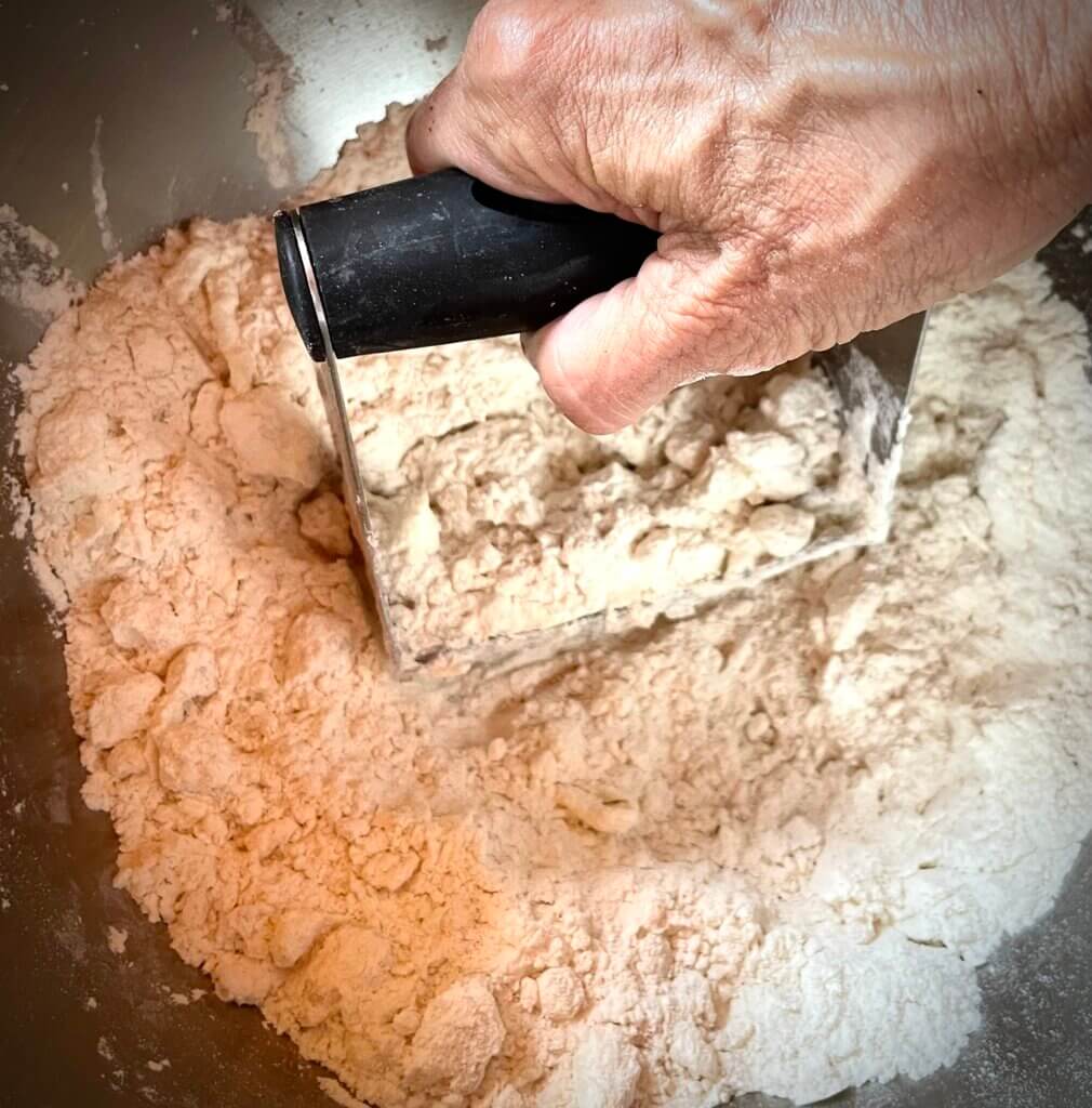 hand working a pastry cutter into dough