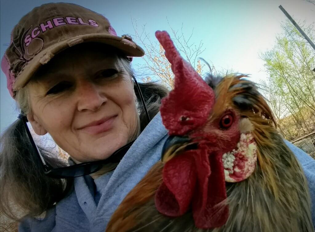 Woman with hat, holding rooster.