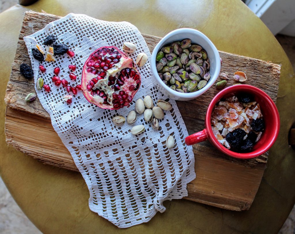 pomegranate, pistachios, and fruits in cups and on a board