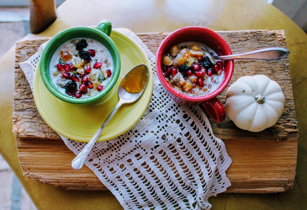 Turkish breakfast porridge recipe in little colorful cups, on lace, across board. honey on spoon