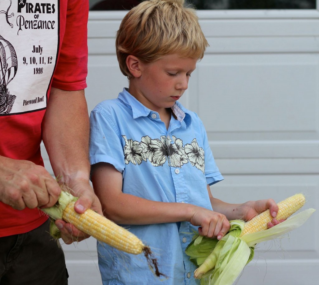 little boy shucking corn