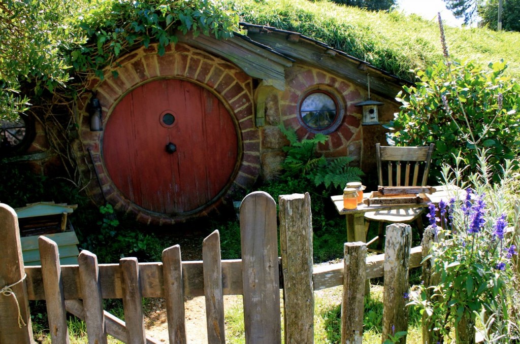 red round door of Hobbit home, with picket fence