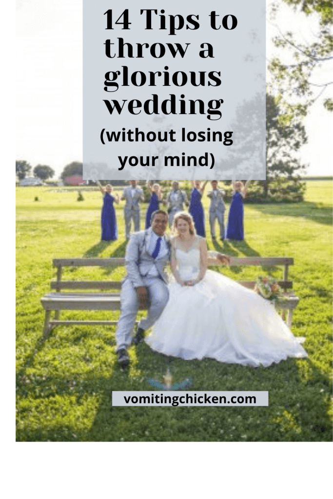 bride and groom sitting with wedding party jumping in the background